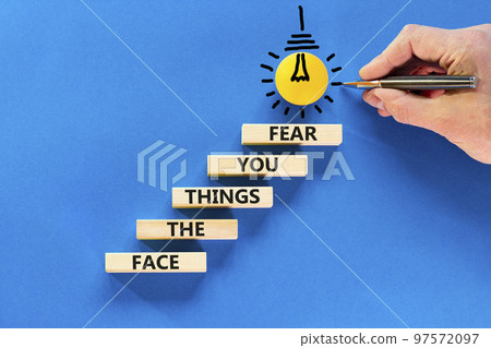 Face the things you fear symbol. Concept words Face the things you fear on wooden blocks on a beautiful blue background. Businessman hand. Business and face the things you fear concept. Copy space. 97572097
