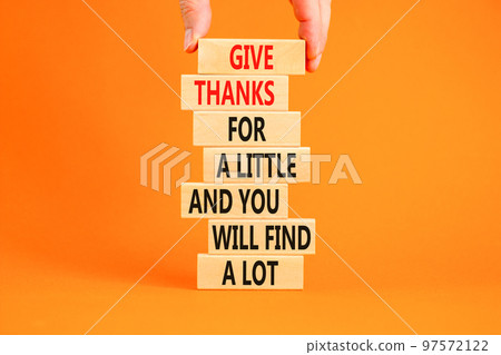Give thanks symbol. Concept words Give thanks for a little and you will find a lot on wooden blocks. Beautiful orange background copy space. Businessman hand. Business motivational give thanks concept 97572122