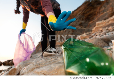 Conservation of ecology and garbage cleanup for recycling. A volunteer take a plastic bottle at the beach. Bottom view. Global environmental pollution 97572886