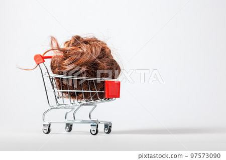 A shopping cart filled with hair on a white background. Copy space. The concept of buying and selling hair A shopping cart filled with hair on a white background. Copy space. The concept of buying and selling hair 97573090
