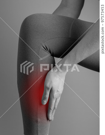 Shin splints. Woman holding painful leg with red point closeup. Muscles, tendons inflammation, medial tibial stress syndrome. Health care, orthopedic problems and medicine concept. Black and white Shin splints. Woman holding painful leg with red point closeup. Muscles, tendons inflammation, medial tibial stress syndrome. Health care, orthopedic problems and medicine concept. Black and white 97573453