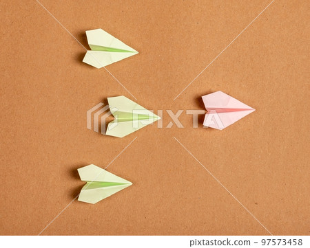 Leadership. Green origami planes and outstanding pink one flying ahead on brown background. Guidance, authority or winning in competition concept 97573458