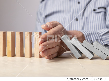 Man hand stopping domino effect. Insurance, risk management concept. Business recovery. Financial crisis, failure, economic recession prevention. Man hand stopping domino effect. Insurance, risk management concept. Business recovery. Financial crisis, failure, economic recession prevention. 97573495