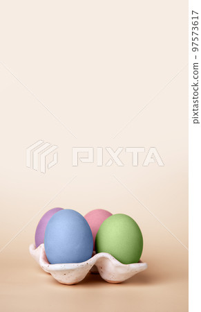 Banner with multicolored Easter eggs in carton box on beige background. Symbol of religious holiday. Copy space 97573617
