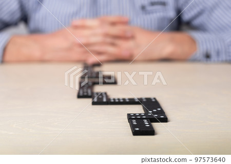 Action plan, strategy, risk assessment concept. Man with crossed hands thinking about next step while playing domino. Action plan, strategy, risk assessment concept. Man with crossed hands thinking about next step while playing domino. 97573640