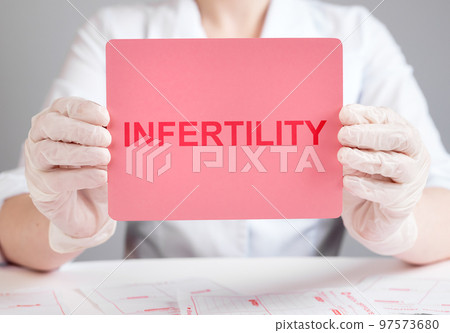 Doctor holding paper with word infertility. Reproductive system diseases diagnosing and treatment. Health care and medicine concept. Woman in lab coat and in gloves 97573680