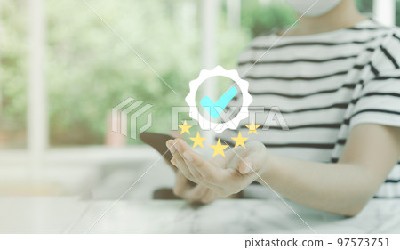 Businesswoman hand holding smartphone and shows the sign of the top service Quality Assurance 5 star, Best guarantee, Warranty standards, ISO certification, and excellent standardization concept. 97573751