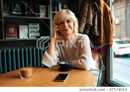 Portrait of adult pretty smiling Caucasian woman sitting in cafe. Concept of psychology and carefree 97574019