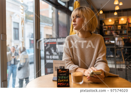 Portrait of adult thoughtful Caucasian woman sitting in cafe and looking out window. Concept of psychology and depression 97574020