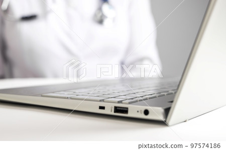 Doctor with stethoscope sitting at desk with laptop. Woman in lab coat giving online consultation to patient. Healthcare and telemedicine concept. Using electronic communications for treatment. Doctor with stethoscope sitting at desk with laptop. Woman in lab coat giving online consultation to patient. Healthcare and telemedicine concept. Using electronic communications for treatment. 97574186