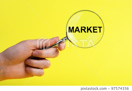 Hand with magnifier with word market on yellow background. Conducting research about new product, service, customers satisfaction assessment. Marketing concept. 97574356