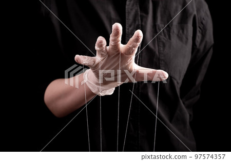 Hand in medical glove with strings on fingers. Deception in medicine and pharmacy, conspiracy theory, health care fraud, spreading false information about diseases, medication. 97574357