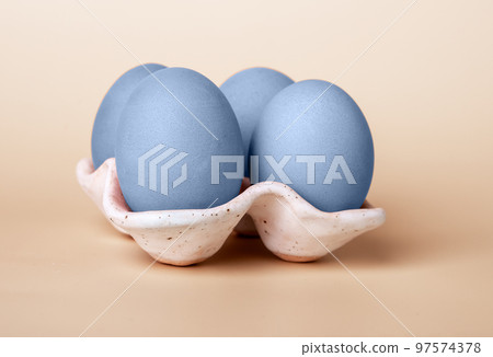 Blue dyed Easter eggs in carton box on beige background. Minimal religious holiday concept 97574378