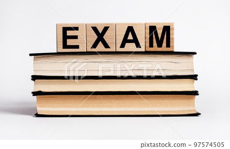 Word exam on Books stack with wooden blocks. Preparation for examination, education concept. Data learning by reading. Getting knowledge from textbook 97574505