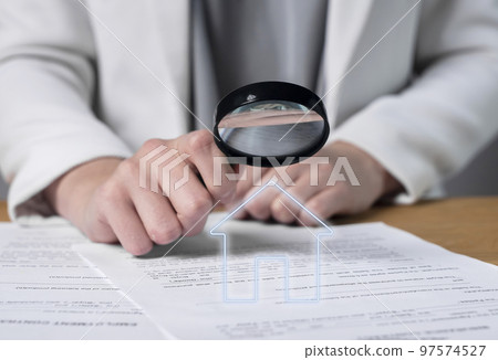 Woman hands holding magnifier and studying real estate purchase, lease or home loan agreement. Thorough analysis of contract terms and conditions. Apartment or house buying or sale 97574527
