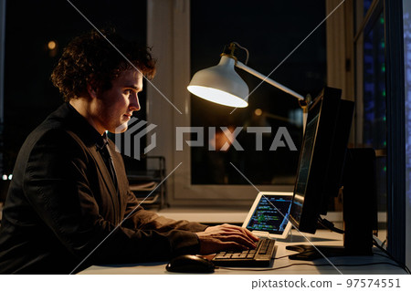 Young programmer writing codes on computer to develop new software, he working overtime in office Young programmer writing codes on computer to develop new software, he working overtime in office 97574551