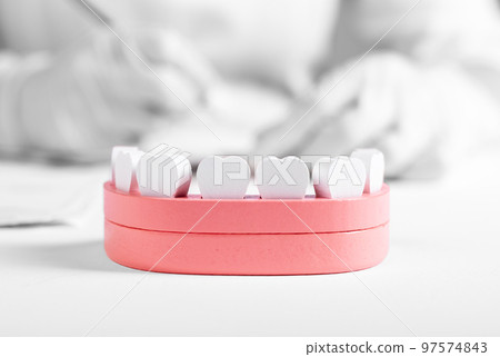 Wooden jaw model with teeth and dentist hands in background. Dental health, oral hygiene, check for tooth disease, stomatology concept. Wooden jaw model with teeth and dentist hands in background. Dental health, oral hygiene, check for tooth disease, stomatology concept. 97574843