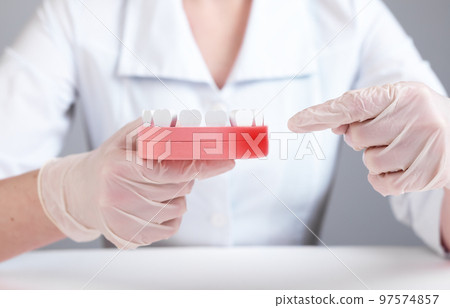 Gingiva inflammation. Dentist forefinger pointing to red spot at jaw model with teeth. Poor oral care habits, infection consequences. Gums diseases treatment. Gingiva inflammation. Dentist forefinger pointing to red spot at jaw model with teeth. Poor oral care habits, infection consequences. Gums diseases treatment. 97574857