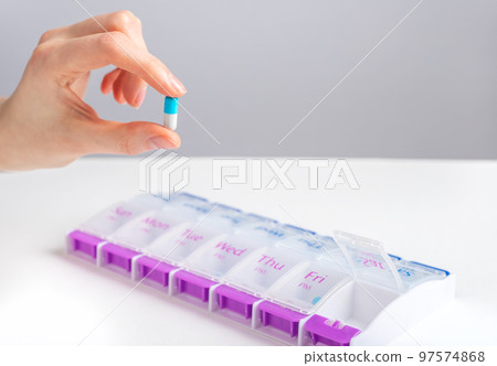 Hand holding pill capsule near tablet case, box Hand holding pill capsule near tablet case, box 97574868