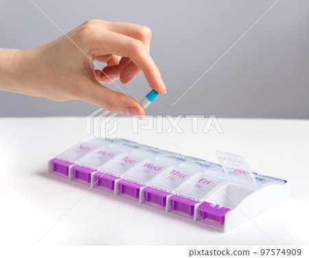 Hand taking capsule from pill case, bbo, organizer 97574909