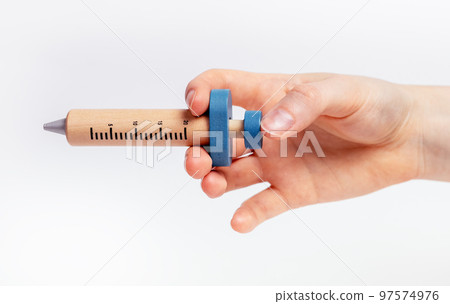 Wood kids syringe toy in female hand closeup, injection 97574976