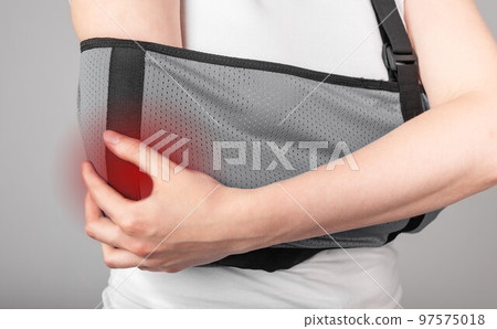 Woman holding painful elbow in sling with red point. Female wearing bandage for supporting arm. Healing process. Fracture, overuse, inflammation consequences. Woman holding painful elbow in sling with red point. Female wearing bandage for supporting arm. Healing process. Fracture, overuse, inflammation consequences. 97575018