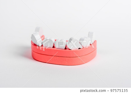 Wooden jaw model with loose crooked teeth. Primary milk tooth loss, replacement with permanent ones. Dental health, stomatology concept Wooden jaw model with loose crooked teeth. Primary milk tooth loss, replacement with permanent ones. Dental health, stomatology concept 97575135