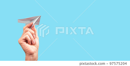 Banner with female hand throwing origami plane on turquoise background. Handmade paper aircraft. Freedom, childhood, fun concept. Place for text 97575204