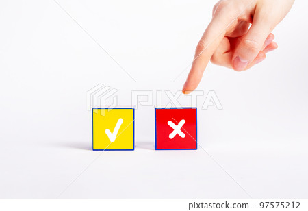Choice between positive and negative decisions, vote concept. Forefinger pointing to red cube with cross instead of yellow one with tick mark. Rejection, disapproval 97575212