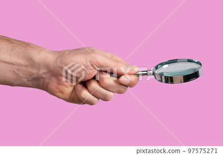Magnifying glass in man hand on pink background. Thorough information study concept, learning details. Spy, accountant, auditor job. Magnifying glass in man hand on pink background. Thorough information study concept, learning details. Spy, accountant, auditor job. 97575271