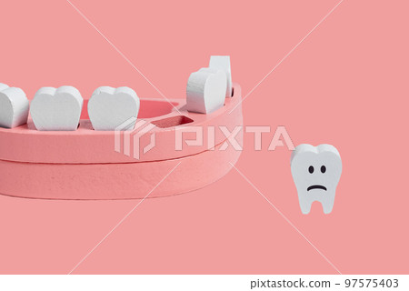 Teeth loss concept. Wooden jaw model with missing or extracted tooth with sad emoji on pink background. Poor oral hygiene, dental problems concept. 97575403