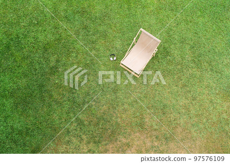 Deck chair with headphones on the green grass sunbathes at summer day. Top view, drone, aerial view. 97576109