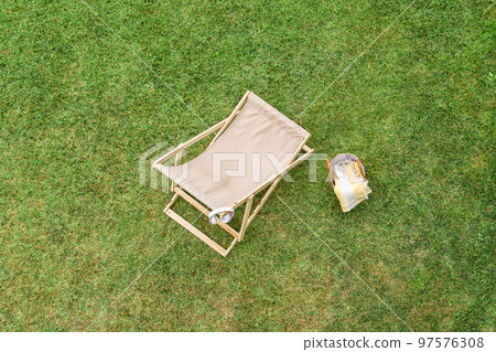 Deck chair, basket for picnic, headphones on the green grass at summer day. Top view, drone, aerial view. 97576308