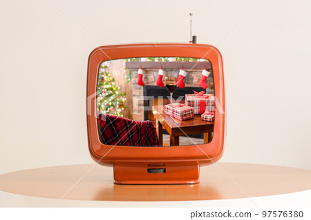 Tv showing movie of Armchair with plaid, packing gift boxes for family and glass of wine near christmas tree and fireplace. Top view . Tv showing movie of Armchair with plaid, packing gift boxes for family and glass of wine near christmas tree and fireplace. Top view . 97576380