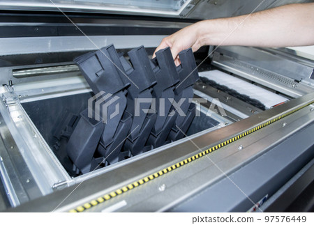 Man takes out model printed 3D printer from the workspace of a big industrial 3D printer. Model printed from polyamide powder. Two workers print an object on a powder 3D printer. Multi Jet Fusion 97576449