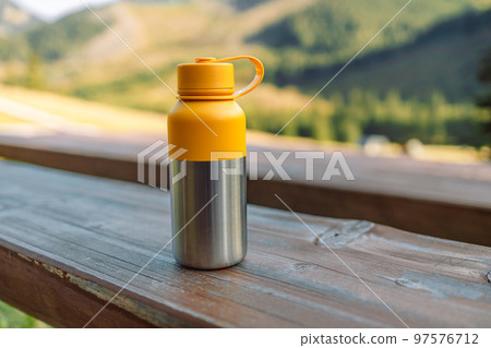 Water bottle on wooden stump in the middle of woods. Reusable steel thermo water bottle on a wood table in forest. Steel thermo water bottle. Be plastic free. Zero waste. Copy space. Zero waste, no Water bottle on wooden stump in the middle of woods. Reusable steel thermo water bottle on a wood table in forest. Steel thermo water bottle. Be plastic free. Zero waste. Copy space. Zero waste, no 97576712