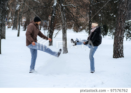 Valentines day outdoors celebration date ideas. Winter love story. Cold season dating for couples. Young couple in love play snowball, hugging and kissing in winter city street and park Valentines day outdoors celebration date ideas. Winter love story. Cold season dating for couples. Young couple in love play snowball, hugging and kissing in winter city street and park 97576762