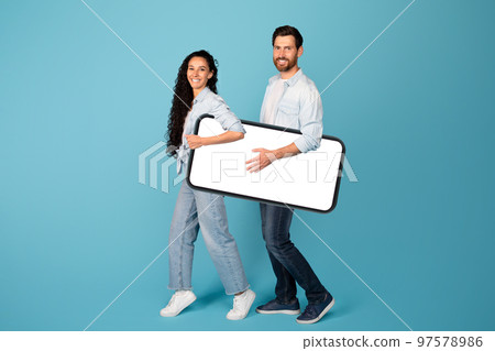 Smiling funny young european guy and woman in casual carry huge smartphone with empty screen Smiling funny young european guy and woman in casual carry huge smartphone with empty screen 97578986