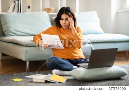 Stressed Arab Female Freelancer Working With Papers And Laptop At Home Stressed Arab Female Freelancer Working With Papers And Laptop At Home 97578990