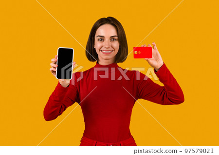 Smiling young woman holding smartphone and credit card, mockup 97579021