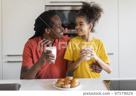 Black Preteen Girl And Her Father Eating Snacks And Bonding In Kitchen 97579029