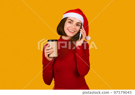 Pretty brunette lady in Santa hat talking on phone 97579045