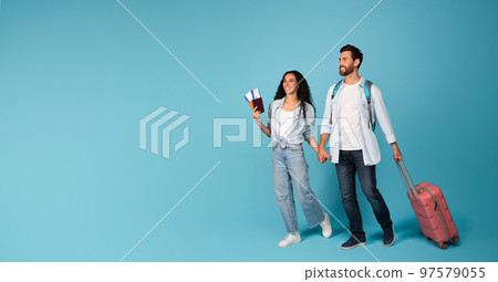 Smiling young guy and lady in casual tourist with suitcase, tickets and passport traveling and look at empty space 97579055