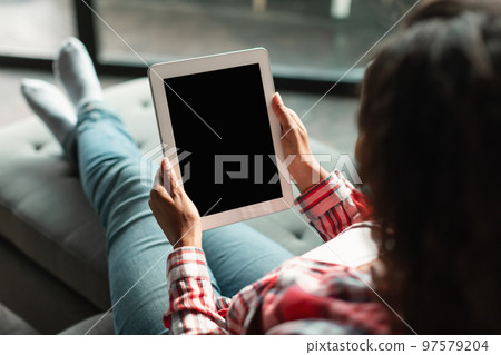 New app for chat. Millennial black female using tablet with blank screen, ordering goods remotely New app for chat. Millennial black female using tablet with blank screen, ordering goods remotely 97579204