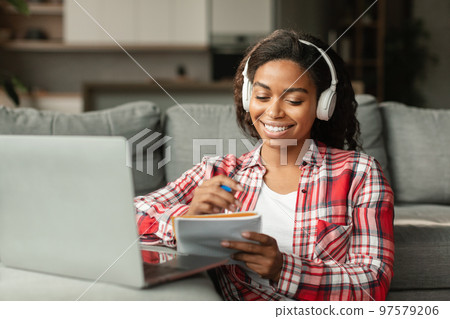 Happy millennial black lady student in wireless headphones study at home with computer 97579206