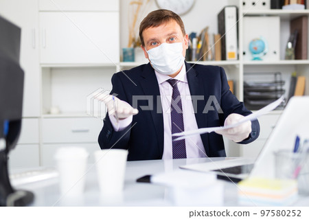 Manager in face mask and gloves discussing business task in office 97580252