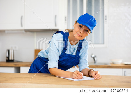 Woman house cleaner making notes in kitchen 97580254