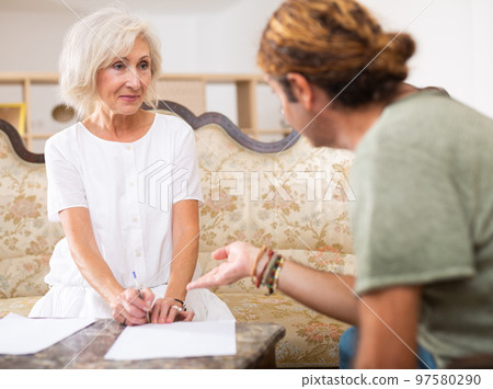 Helpful man helping elderly woman to sign documents 97580290
