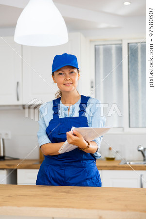 Woman house cleaner making notes in kitchen 97580302