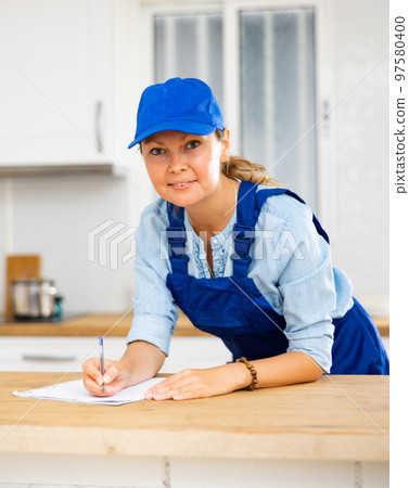 Woman house cleaner making notes in kitchen 97580400